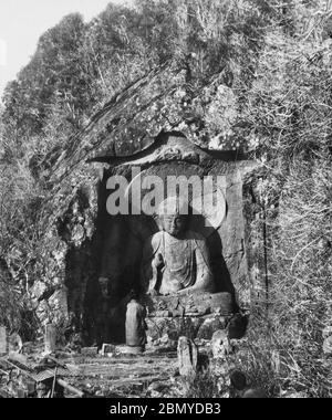 [ 1890s Japan - Japanese Buddhist Statue ] —   Praying at a statue of the Buddhist deity of Jizo in Hakone, Kanagawa Prefecture.  Known as the Rokudo Jizo (六道地蔵), it is a 3.5 meter tall Buddha figure carved on a rock face, dating from the Kamakura period (1185-1333).  From a series of glass slides published (but not photographed) by Scottish photographer George Washington Wilson (1823–1893). Wilson’s firm was one of the largest publishers of photographic prints in the world.  19th century vintage glass slide. Stock Photo