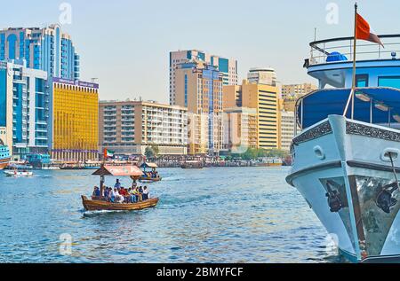 DUBAI, UAE - MARCH 2, 2020: The abra boat floats along Dubai Creek with a view on moored ship and modern quarters of Deira, on March 2 in Dubai Stock Photo