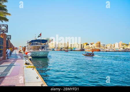 DUBAI, UAE - MARCH 2, 2020: Walk along the bank of Al Fahidi district and watch abra and dhow boats, floating along Dubai Creek, on March 2 in Dubai Stock Photo