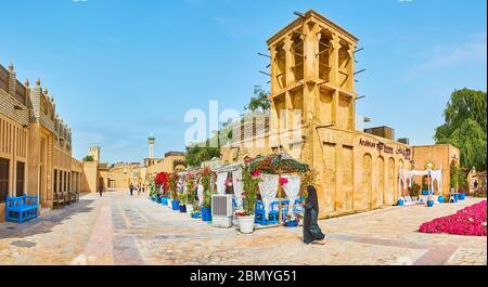 DUBAI, UAE - MARCH 2, 2020: Panorama of historical Al Bastakiya (Al Fahidi) neighborhood with adobe housing, tall barjeel windcatchers and outdoor tea Stock Photo