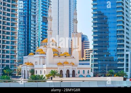 The facade, domes and minarets of Mohammed Bin Ahmed Al Mulla Mosque, sandwiched between the modern high rises of Dubai Marina, UAE Stock Photo