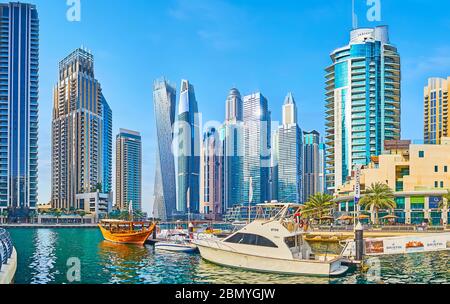 DUBAI, UAE - MARCH 2, 2020: Dubai Marina cityscape with a view on canal, harbor of Bristol Charter with moored wooden dhow boat and motor boats, on Ma