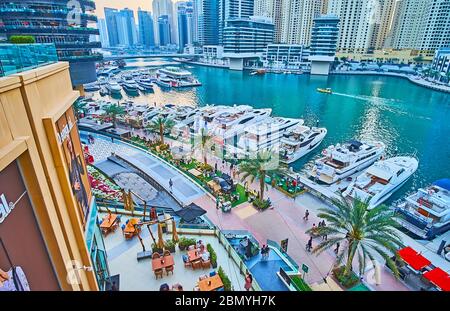 DUBAI, UAE - MARCH 2, 2020: The top view on the outdoor cafes of Marina Mall, palm tree alley and yacht club of Dubai Marina, on March 2 in Dubai Stock Photo