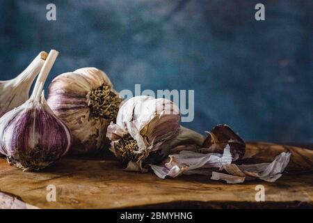 garlic bulbs on a wooden cutting board with a dark blue background Stock Photo