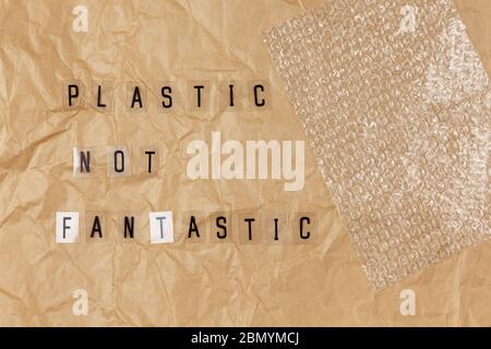 Bubble wrap, phrase from letters on transparent base Plastic not fantastic on brown crumpled craft paper. Eco, zero waste concept. Flat lay, top view. Stock Photo