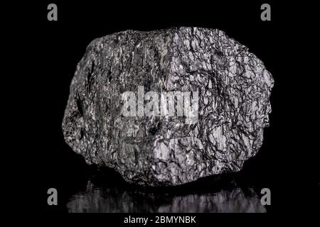 A lump of brown coal laid on a table. Mineral used to generate energy. Dark background. Stock Photo