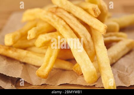 French fries in a paper on wooden table. Close up Stock Photo