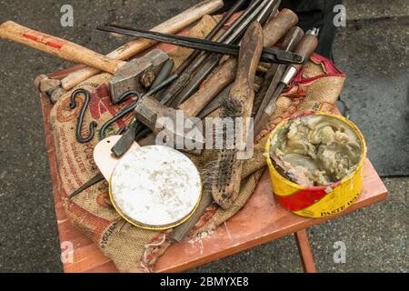 Puyallup, Washington, USA.   Variety of blacksmith hammer, tongs, brush and other tools resting on a table. Stock Photo