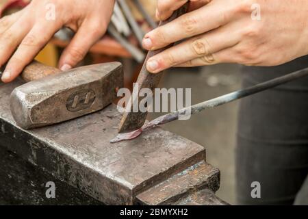 Puyallup, Washington, USA.   Female blacksmith working a leaf pattern on a hot iron. Stock Photo