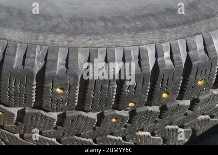 Tread of an old car winter tire with dropped spikes close-up. Worn winter tires. Stock Photo
