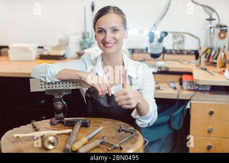 Portrait of a goldsmith in her workshop standing amidst tools