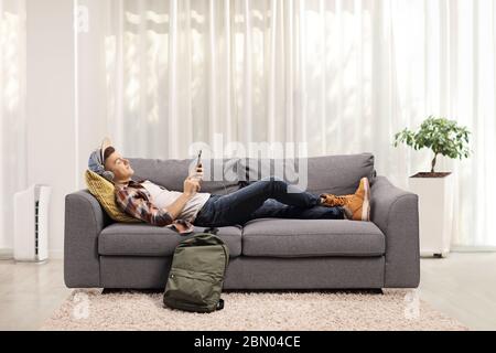 Guy lying on a sofa at home and listening to music on headphones Stock Photo