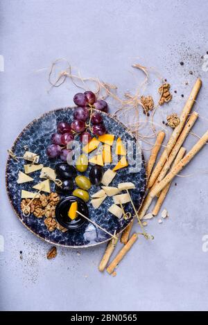 Cheese plate appetizer for party, cheese assortment platter with grapes, honey and nuts, flat lay. Grey concrete background. Stock Photo