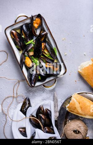 Mussels or clams, shellfish in a bowl on light background, text space. Overhead view. Stock Photo