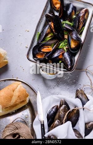 Mussels or clams, shellfish in a bowl on light background, text space. Overhead view. Stock Photo