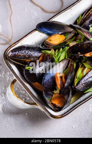 Mussels or clams, shellfish in a bowl on light background, text space. Overhead view. Stock Photo