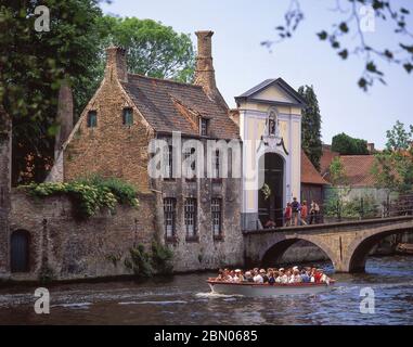 Sightseeing canal boat passing The Beguinage (Begijnhuiseje), Bruges (Brugge), West Flanders Province, Kingdom of Belgium. Stock Photo