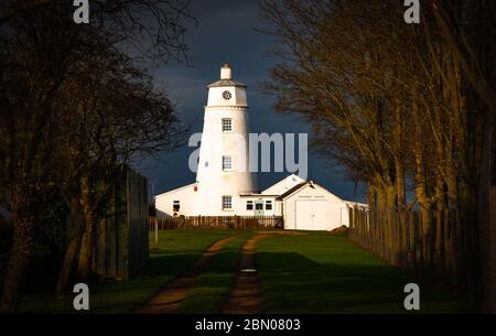 Winter sunlight falling on East Bank Lighthouse famous for The Snow Goose, against a stormy sky in Sutton Bridge, River Nene, Spalding, Lincolnshire Stock Photo