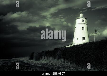 Winter sunlight falling on East Bank Lighthouse famous for The Snow Goose, against a stormy sky in Sutton Bridge, River Nene, Spalding, Lincolnshire Stock Photo