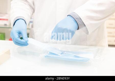 The hands of pharmacist salesman that wears hygiene gloves sells surgical masks Stock Photo