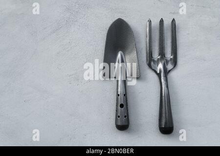black grey metal fork and trowel on cement wall background tool for gardening or agriculture activity Stock Photo