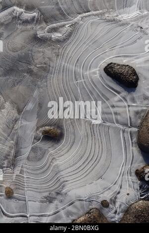 Close-up of ice formations with elegant lines and and river rocks during spring melt along the Yukon River. Nature's creative chaos and random eleganc Stock Photo