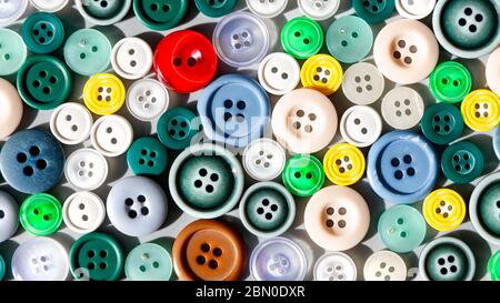 Colorful mixed sewing buttons lit by sunlight, flat lay. Items for sewing clothes.  Top view Stock Photo