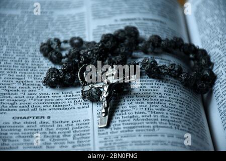 Holy rosary beads laying on a Christian bible. Stock Photo