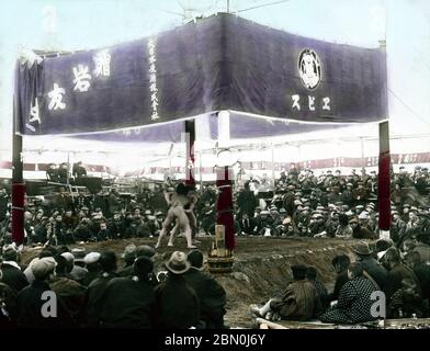 [ 1900s Japan - Outside Sumo Wrestling Arena at Temple ] —   Sumo wrestlers in an outside arena at Eko-in Temple (回向院) in Ryogoku, Tokyo ready to start a bout.   The temple was known as a sumo wrestling venue during the Edo (1603-1868) and Meiji (1868-1912) periods.  The first bout was held here in September 1768. From October 1833 (Tenpo 4) to 1909 (Meiji 42), the period of “Eko-in Sumo” (回向院相撲), all sumo tournaments were held at the temple.  19th century vintage glass slide. Stock Photo