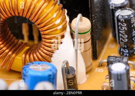 Old vintage printed circuit board with electronic components. Electronic Coil in the foreground. Closeup with shallow DOF . Stock Photo
