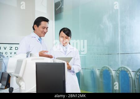 Smiling assistant showing medical history of patient to ophthalmologist Stock Photo