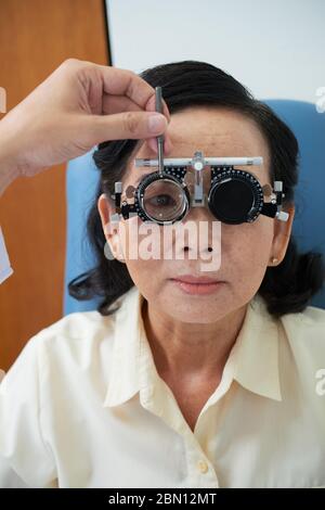 Senior Vietnamese woman having her eyes examined at ophthalmology clinic Stock Photo