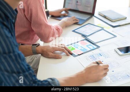 Graphic designers team work together with UX UI designer planning application template layout mobile phone prototype, User experience concept. Stock Photo
