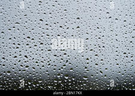 Rain drops on glass window. Dark grey textured background. Full frame macro photo.  Stock Photo