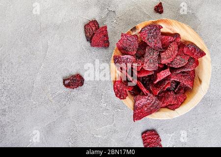 Diet healthy eating concept. Dried beet chips or baked beets in a wooden bowl, on a gray concrete background. Organic natural food. Copy space. Stock Photo