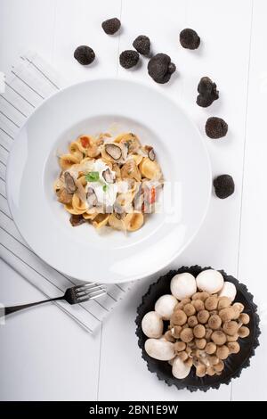 Orecchiette pasta with ceps, cherry tomatoes, ricotta gratin, fresh truffles and wild mushrooms. Orecchiette are a pasta typical of Apulia, a region o Stock Photo