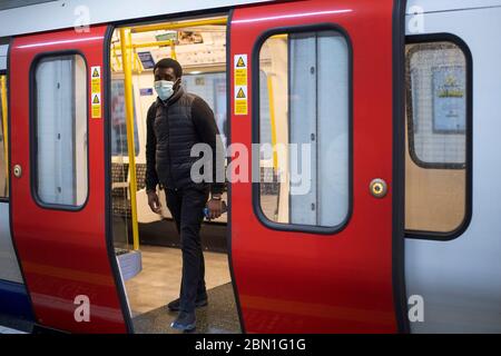 A man wears a face mask on the London Underground District line during what would normally be the evening rush hour, as the UK continues in lockdown to help curb the spread of the coronavirus. Stock Photo