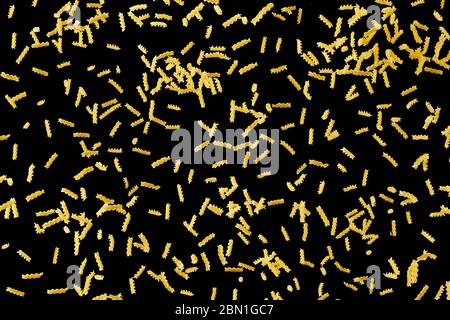 Italian flying raw pasta isolated on black background. macaroni fusilli falling. Stock Photo