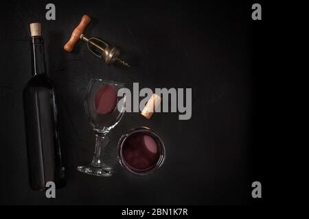 Wine tasting, top shot on a black background, with a cork, a vintage corkscrew, a bottle and two glasses Stock Photo