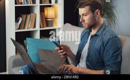 Man using phone and laptop Stock Photo