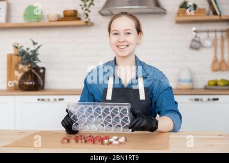 Confectioner girl holds form for candy made of Belgian chocolate. Stock Photo