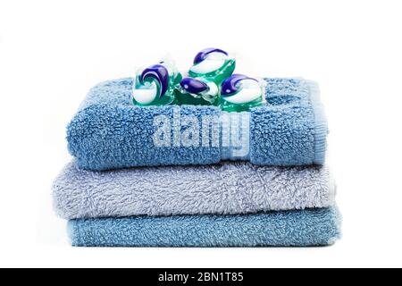 Washing machine detergent pods on blue towels isolated on white background Stock Photo