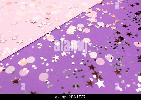 Rose gold confetti texture on a purple background. Festive glowing backdrop. Stock Photo