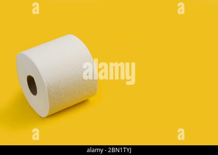 Toilet paper roll on a yellow background with copy space