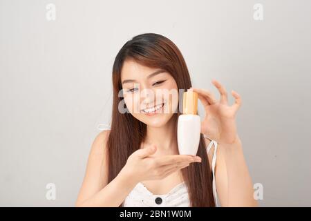 Portrait beautiful asia woman showing product with white cosmetic tube plastic in hand on white background Stock Photo