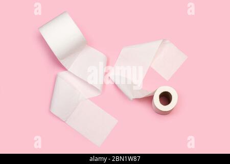 Two toilete paper rolls on a pink background in a top view