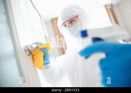 Disinfection and cleaning door handles of house from infection with virus and microbes in biochemical suit. Coronavirus protection concept Stock Photo