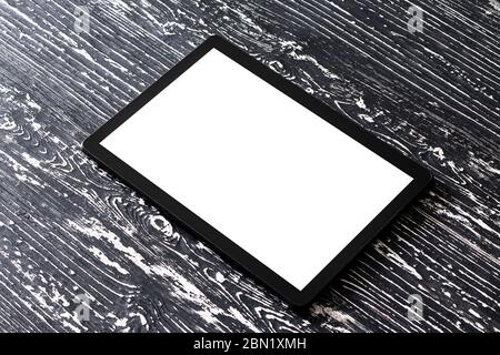 Black tablet with white screen on a wooden table. Copy space display. Blank for design. Stock Photo