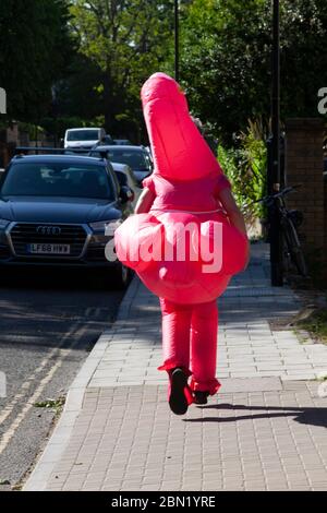 London, UK, 12 May 2020: Clapham chef Fred Smith, 38, is running the equivalent of 4 marathons (168.8 km) for The Felix Project charity, to feed people during the coronavirus lockdown. As part of the Flat Iron Fundraisers Club, Fred has been pounding the streets of Clapham where passersby are delighted or bemused. By searching Just Giving for Flamingo Freddo people have donated over £2700 so far. Anna Watson/Alamy Live News Stock Photo