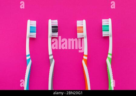 Multicolored toothbrushes on a pink background. The view from the top. Close up.The concept of dental health. Stock Photo